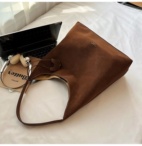 Detailed texture of brown matte leather tote bag with white logo in a lifestyle setup