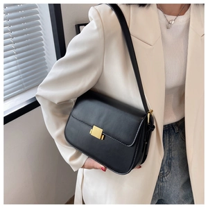 Detail of a black leather crossbody bag featuring a golden rectangular metal clasp