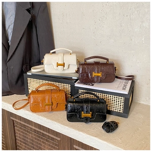 Detail view of four textured leather handbags with gold H-buckles in urban office setting