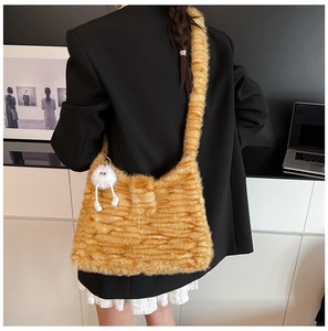 Detail of orange striped fuzzy shoulder bag with cute white plush monster pendant detail