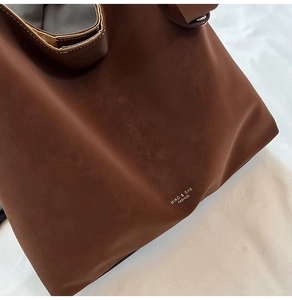 Close-up of matte brown tote bag showing fine stitching and Miao & She brand logo