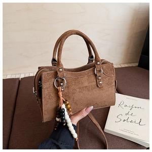 Détail d'un sac à main en daim marron avec pendentif décoratif en perles colorées