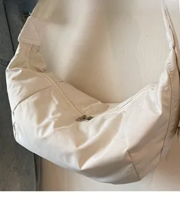 Close-up of the beige crescent shoulder bag showing reinforced stitching and nylon texture