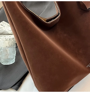 Detail of dark brown suede tote bag featuring MIAO B branding and precision stitching