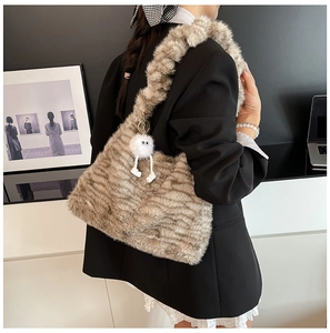 Detail of tiger print faux fur shoulder bag featuring a soft white plush ball pendant