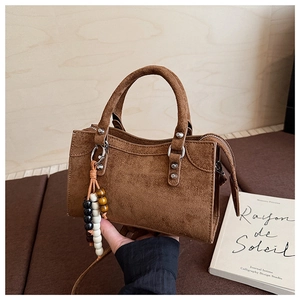 Gros plan d'un sac à main en daim marron foncé avec perles en bois et fermeture éclair