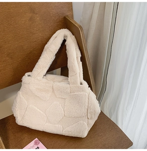 Detail of beige faux fur tote bag showing fluffy geometric texture on a wooden chair