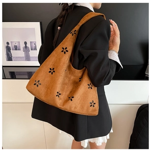 Detailed laser-cut flower pattern on brown suede tote bag shown on model's shoulder