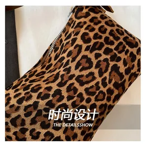 Detail of leopard print fabric with silver metal zipper and brown leather puller on bag