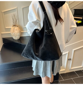 Detail of MIAO & SHE black faux suede tote bag featuring white logo and adjustable strap
