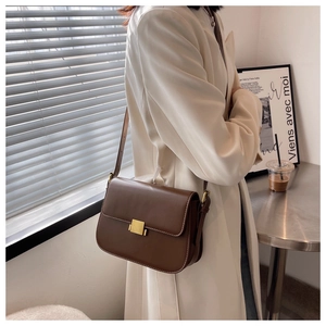Detail of a vintage coffee brown leather crossbody bag with a gold square metal lock