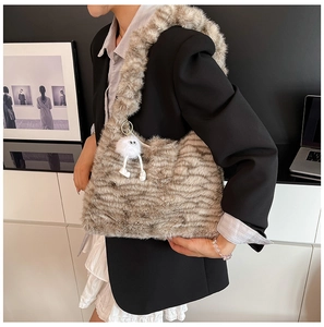 Close-up of fluffy faux fur shoulder bag with striped texture and monster charm