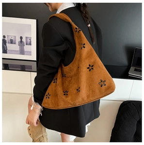 Detail of brown suede hobo bag with intricate floral laser-cut patterns and textures