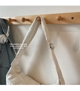 Detail of adjustable silver buckle on off-white nylon crossbody dumpling bag strap