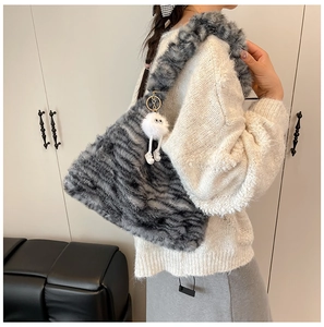 Detail view of large tiger print faux fur shoulder bag with white plush monster charm