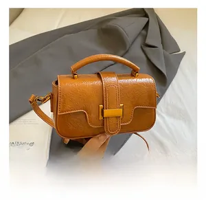 Detail showing the retro crinkled texture and metal clasp of the brown crossbody bag