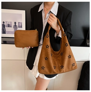 Detail of brown suede tote bag with flower cutouts and matching inner pouch on model