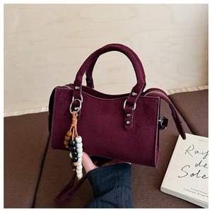 Détail du sac à main bordeaux en daim avec bords ondulés et breloque en perles colorées