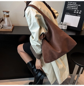 Macro shot of brown suede hobo bag with a wide shoulder strap and metal ring detail