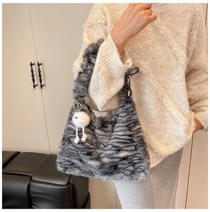 Detail of plush faux fur shoulder bag with mixed grey texture and cute monster charm