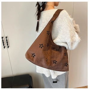 Close-up of brown suede shoulder bag featuring intricate laser-cut floral hollow details