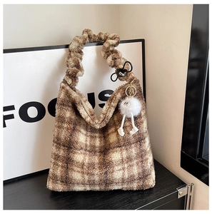 Détail d'un sac cabas en peluche à carreaux marron avec poignée froissée et pendentif
