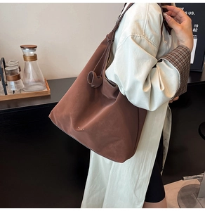 Detail view of deep coffee oversized tote bag in soft matte leather with minimal logo