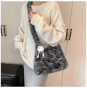 Detailed texture of fuzzy striped faux fur tote bag with a cute monster plush charm
