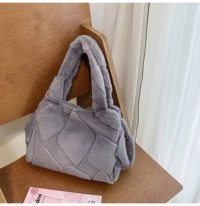 Detail of grey faux fur tote bag with plush quilted texture on a wooden chair