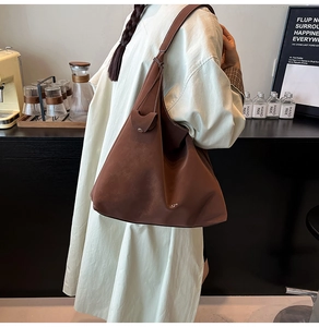 Close-up of the large capacity coffee brown suede tote bag with gold logo on shoulder