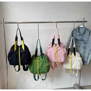 Detail of lightweight nylon drawstring backpacks in black, green, pink and beige colors