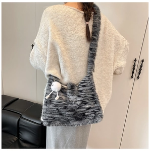 Detail of plush faux fur shoulder bag featuring grey striped animal pattern and pompom