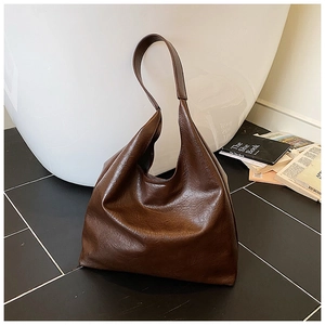 Gros plan d'un grand sac cabas vintage marron en similicuir texturé sur fond céramique