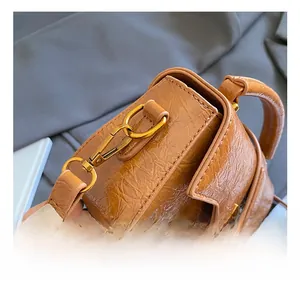 Close-up of caramel leather bag with crinkle texture and gold metal hardware hook