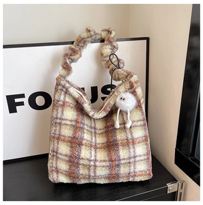 Détail du sac hobo en peluche à carreaux avec breloque monstre et poignée froissée