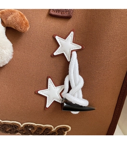 Détail macro du sac en toile avec écussons d'étoiles et fermeture à boucle en corde
