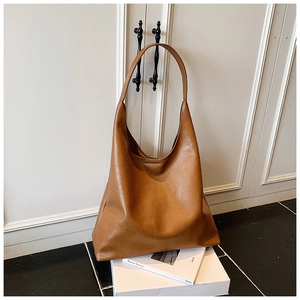 Gros plan sur le sac fourre-tout en cuir marron montrant le grain naturel et la sangle