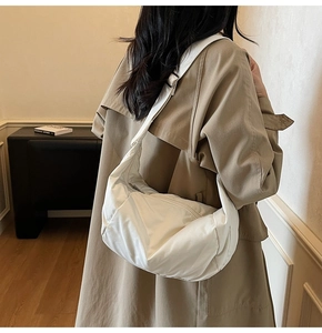 Rear view of a model wearing a stylish white nylon hobo bag with an adjustable wide strap