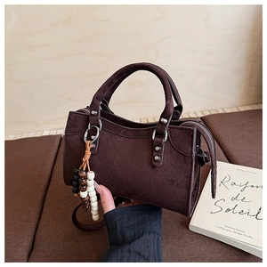 Détail du sac à main vintage en daim marron avec rivets argentés et breloque en perles