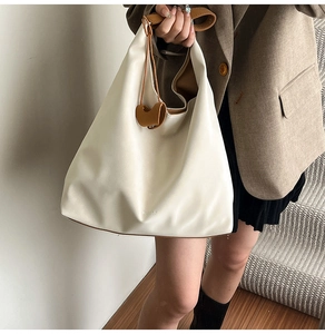 Close-up of a cream oversized tote bag in soft leather with brown interior accents