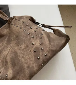 Close-up of vintage brown shoulder bag featuring retro metal studs and textured fabric