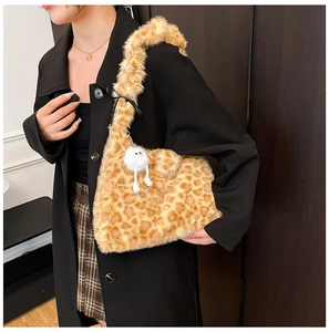 Plush leopard print shoulder bag with white pom-pom charm shown styled on a black coat