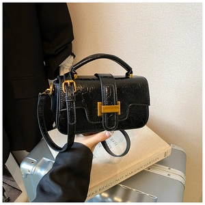 Detail of vintage black patent leather bag with gold buckle and crinkled texture