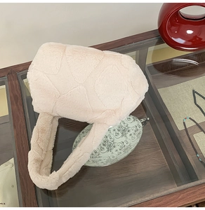 Close-up of cream faux fur tote bag with star pattern quilting on a glass table
