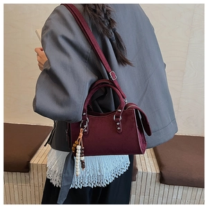 Détail du sac à main en daim bordeaux avec rivets argentés et charme de perles coloré