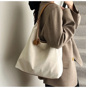 Detail shot of ivory tote bag with textured faux leather and contrasting brown shoulder straps