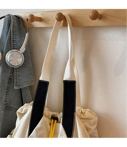 Detail of canvas tote bag showing soft beige fabric and yellow drawstring closure