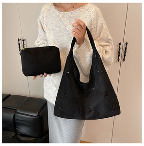 Detail of black suede tote bag set with floral laser-cut patterns and inner pouch