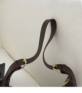 Close-up of dark brown leather strap with adjustable gold buckle on a retro shoulder bag
