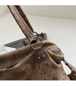 Close-up of vintage brown tote with metallic rivets and round ring handle details